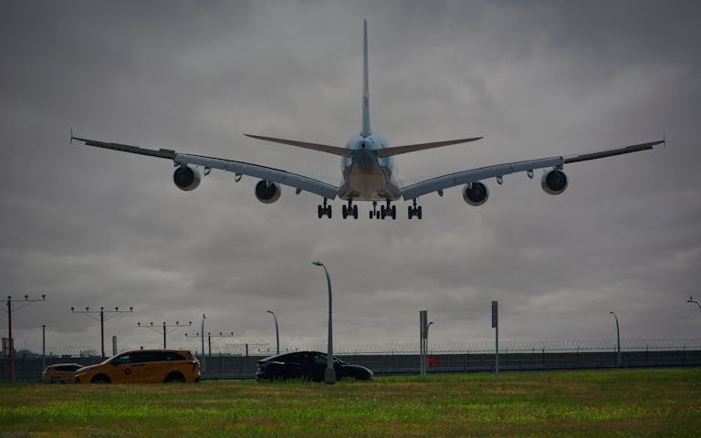 A passenger airplane lands at New York airport with cloudy skies, showcasing aviation and urban transport.