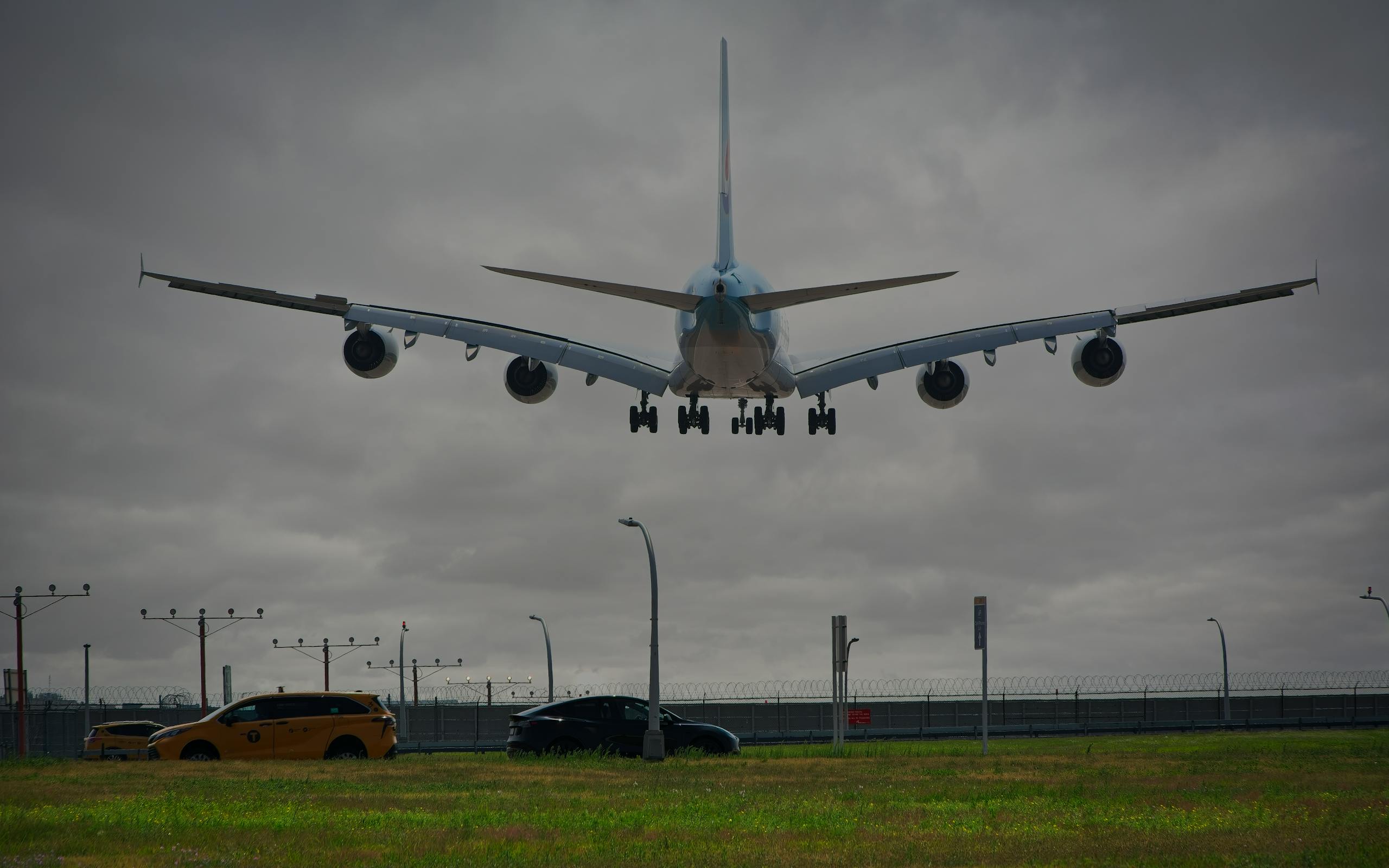 A passenger airplane lands at New York airport with cloudy skies, showcasing aviation and urban transport.