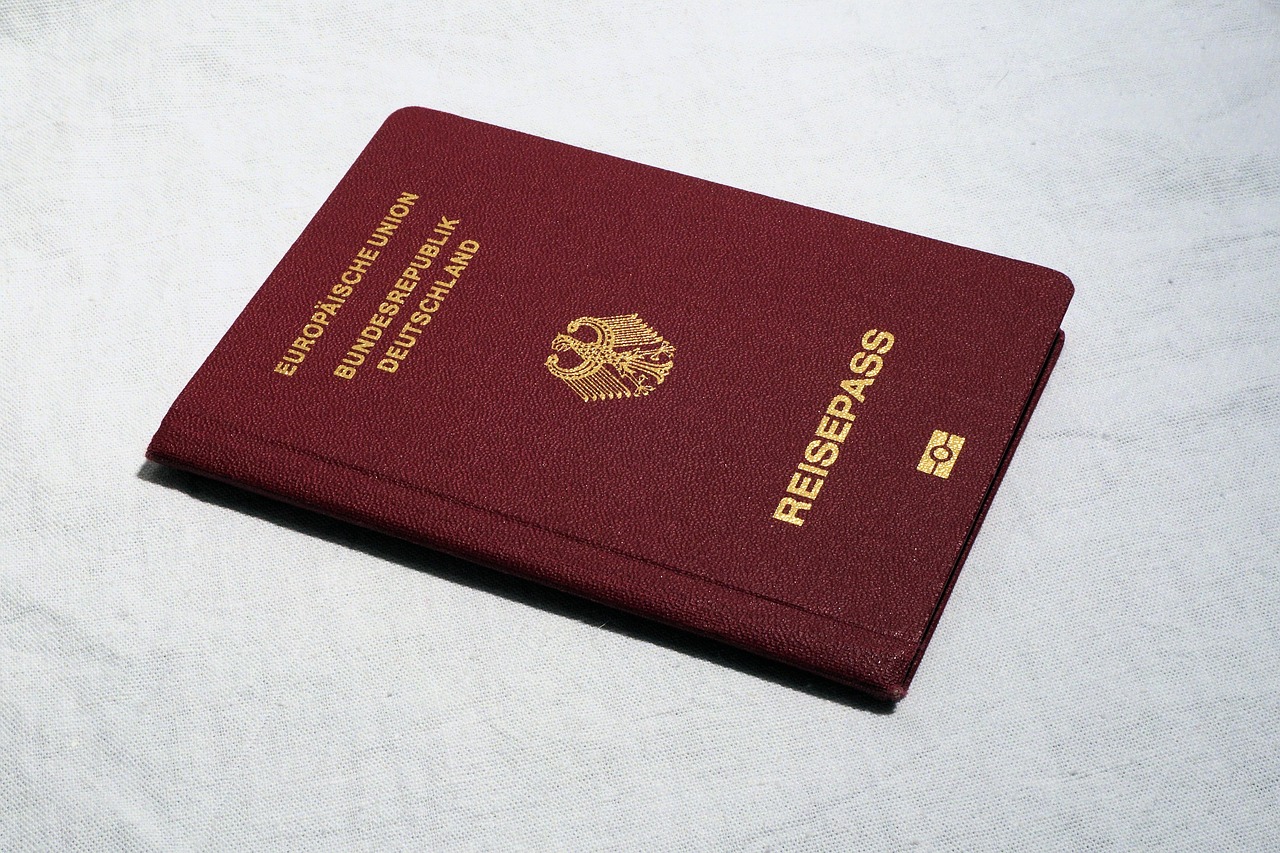 Ruka držící lupu nad dokumentem s drobným písmem a symboly peněz.